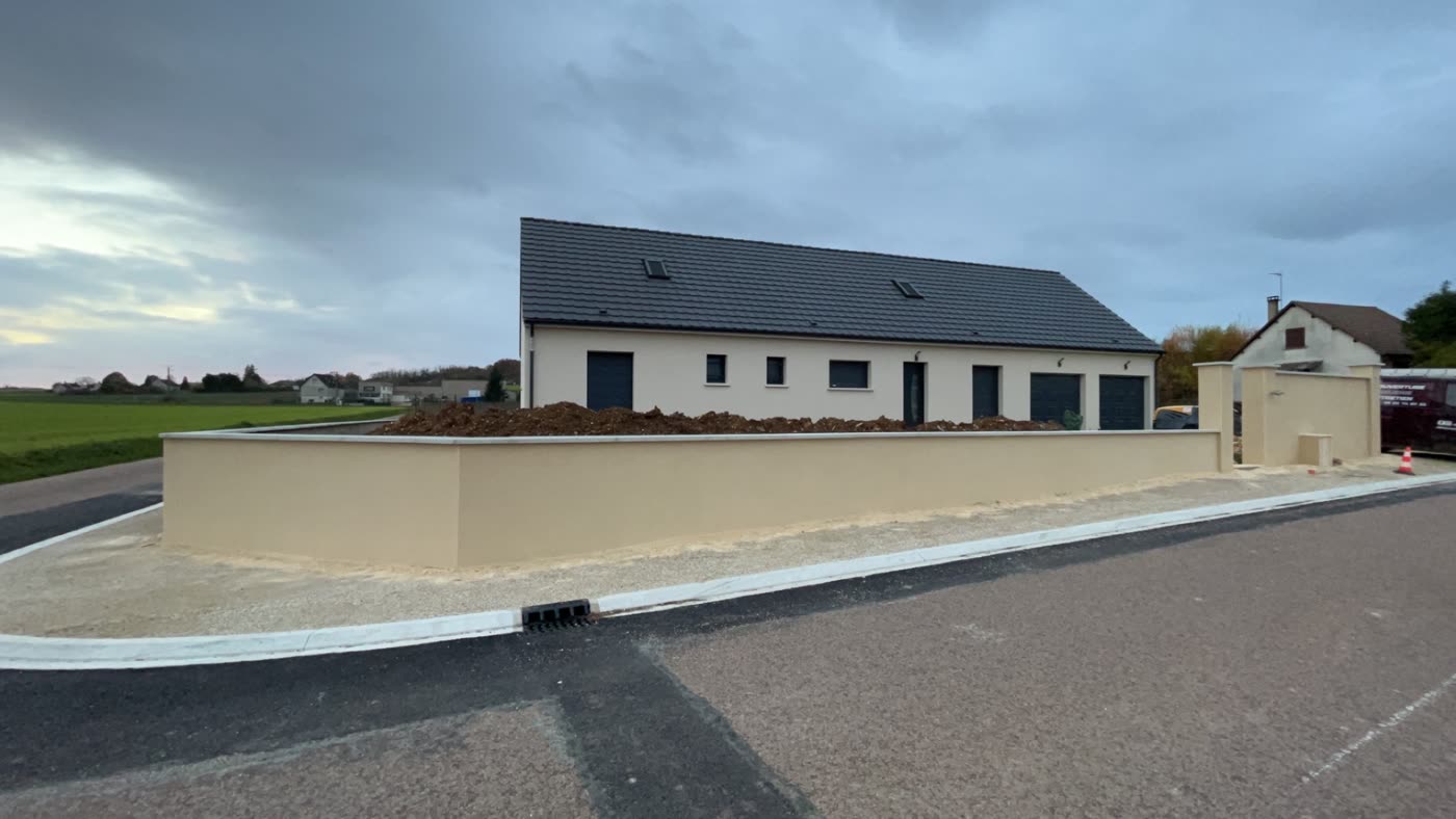 Mur de clôture enduit et terminé, avec ses piliers, le long de la rue