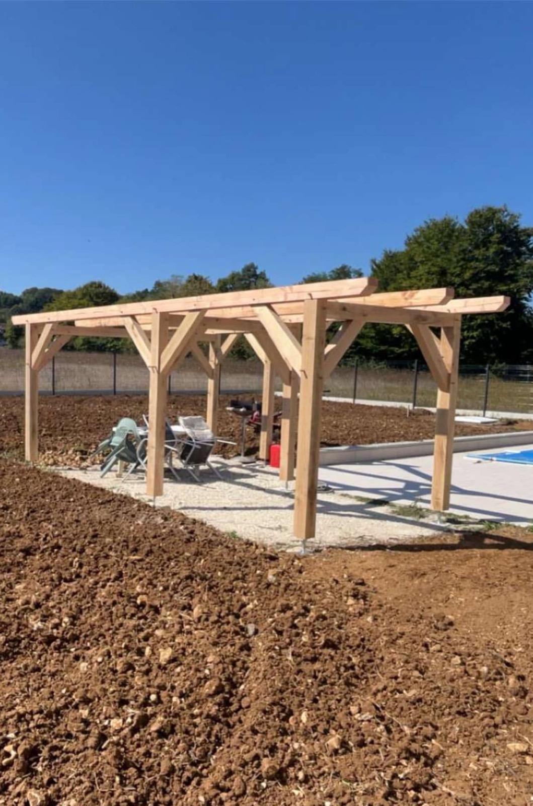 Pergola en bois massif avec jambes de force, posée au bord d'une piscine